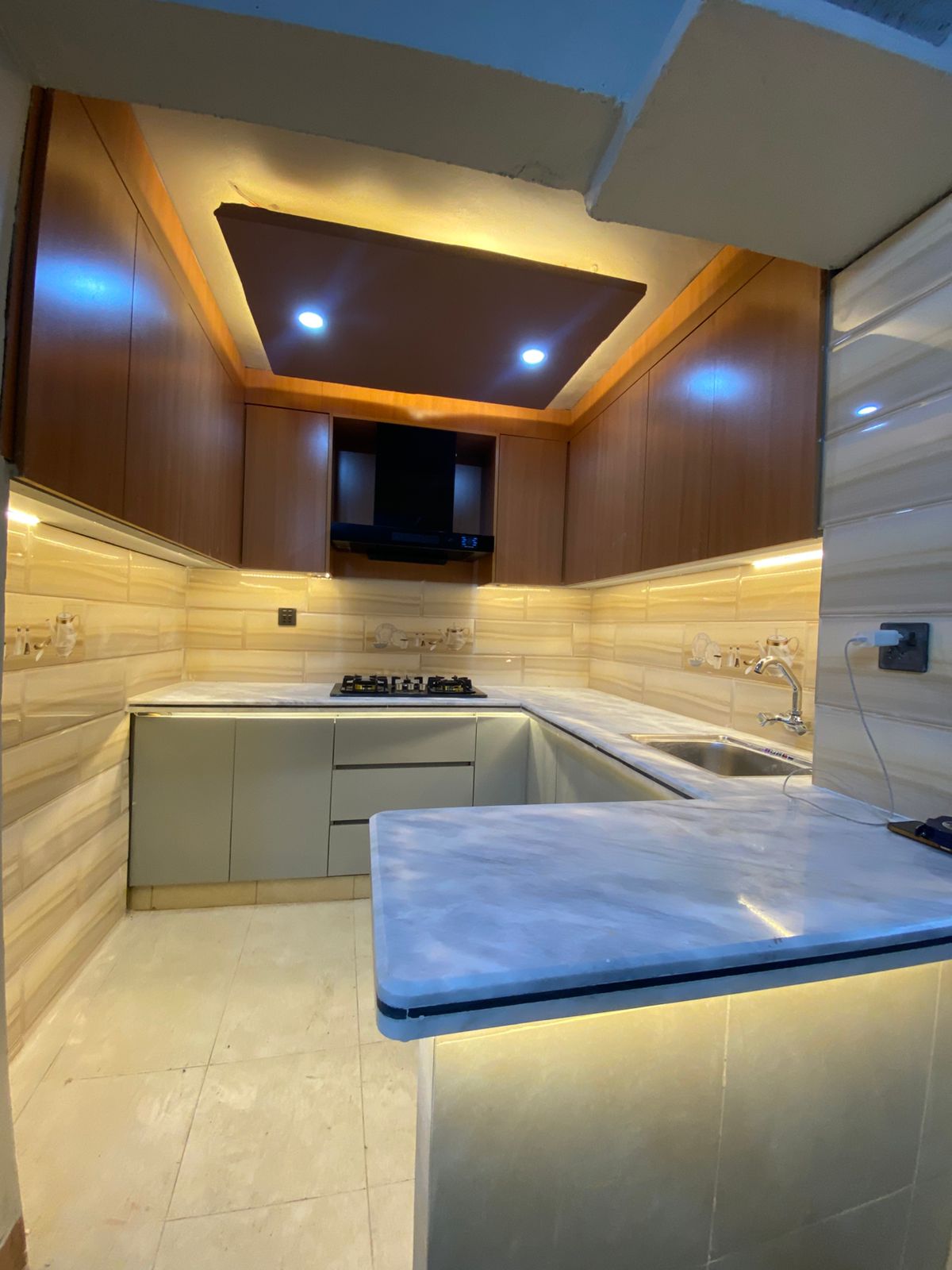 Small kitchen designed with lamination sheet cabinets and Ziarat white grey marble countertop in Karachi by Etminaan Services.
