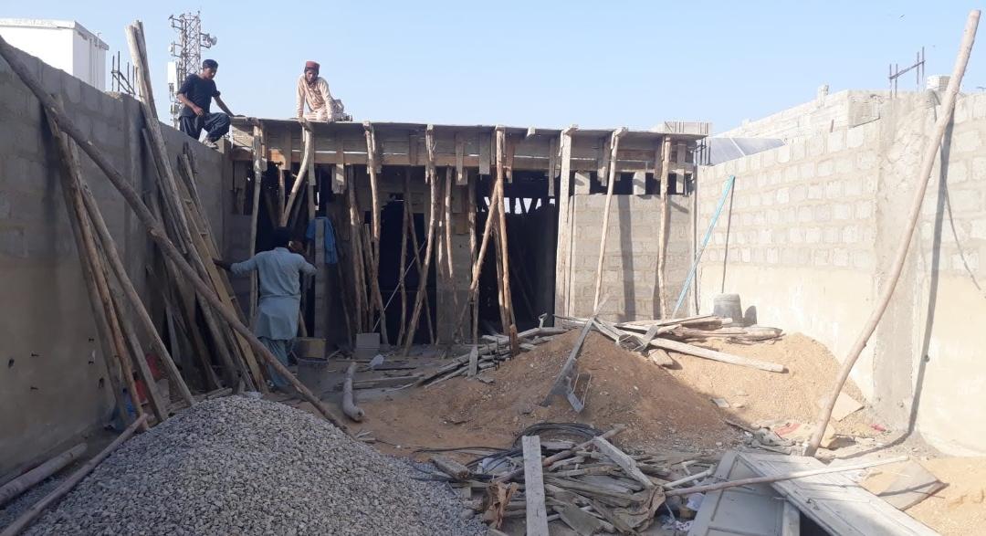 Masonry work in progress for a water tank tower on the fourth floor of a residential building, including brick masonry and wall plastering by Etminaan Services in Karachi.
