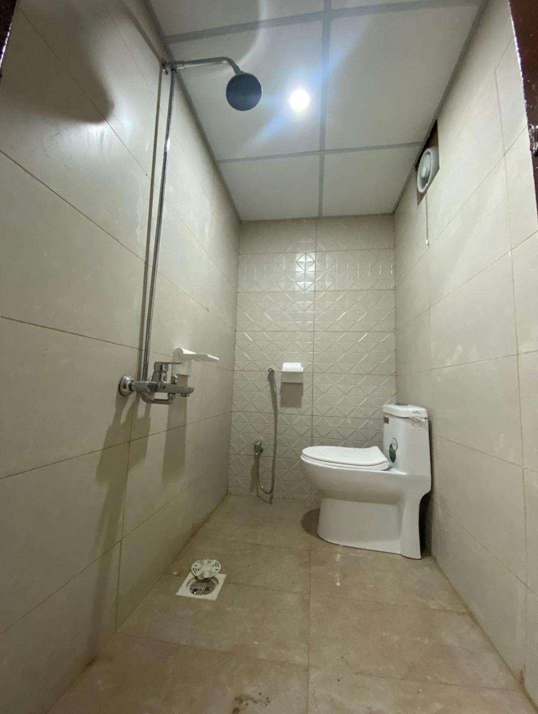 Fully renovated bathroom with new wall and floor tiles, smooth plaster finish, and sanitary fittings completed by Etminaan Services in Karachi.
