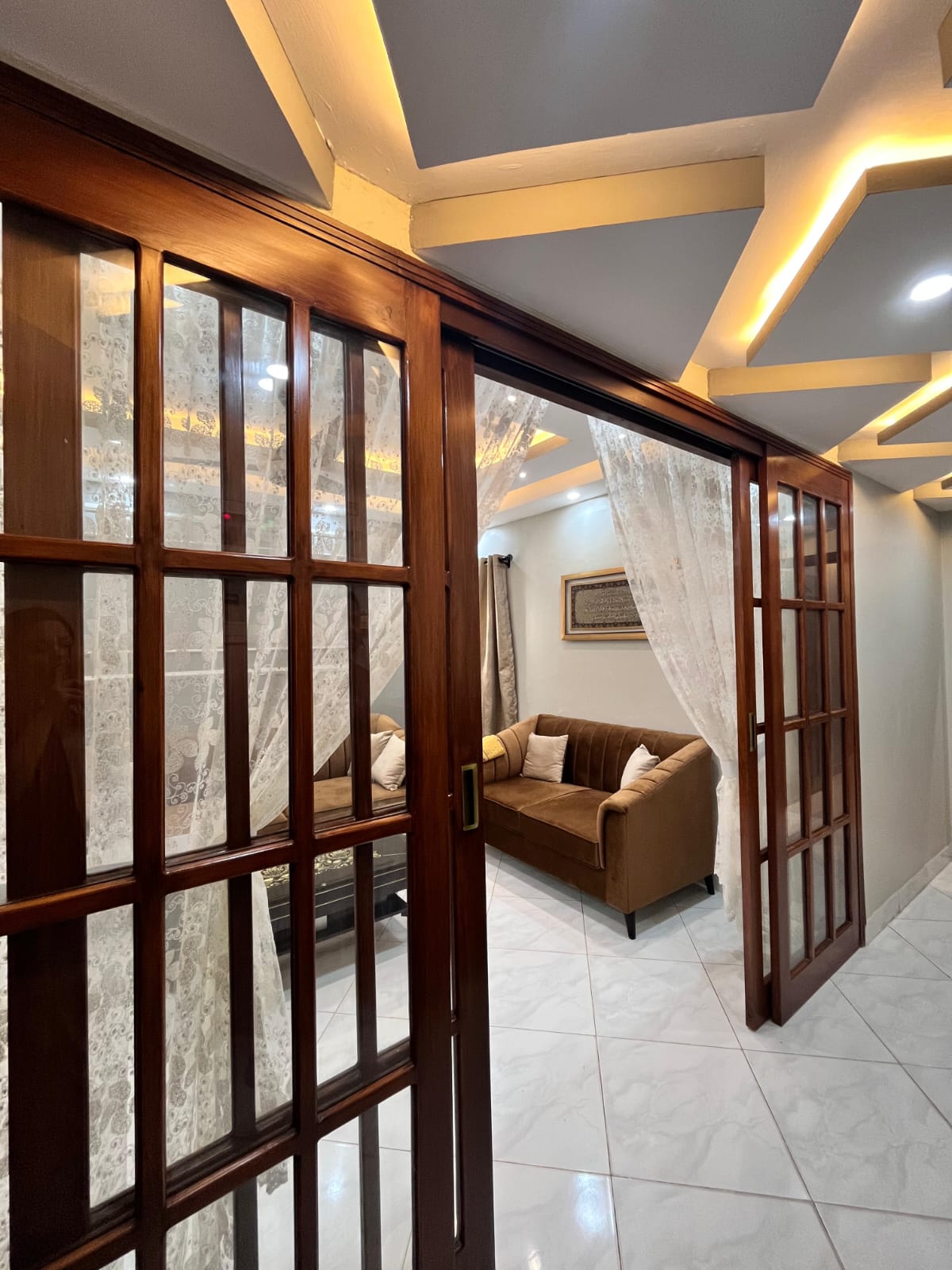 Modern corridor with gypsum false ceiling and wooden glass sliding door completed by Etminaan Services.