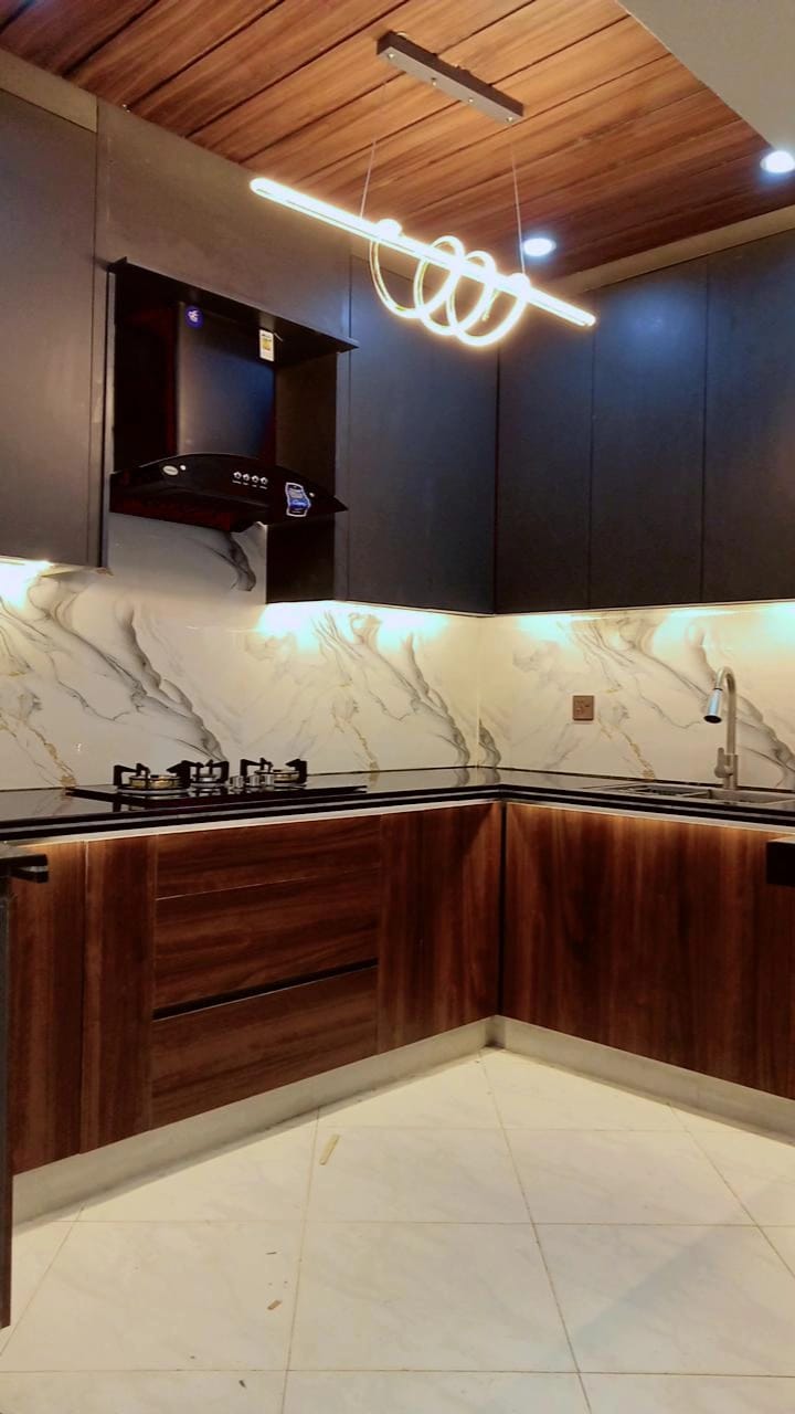 Etminaan Services completed a modern handleless kitchen with brown tactile sheet base cabinets and grey upper cabinets in Karachi.