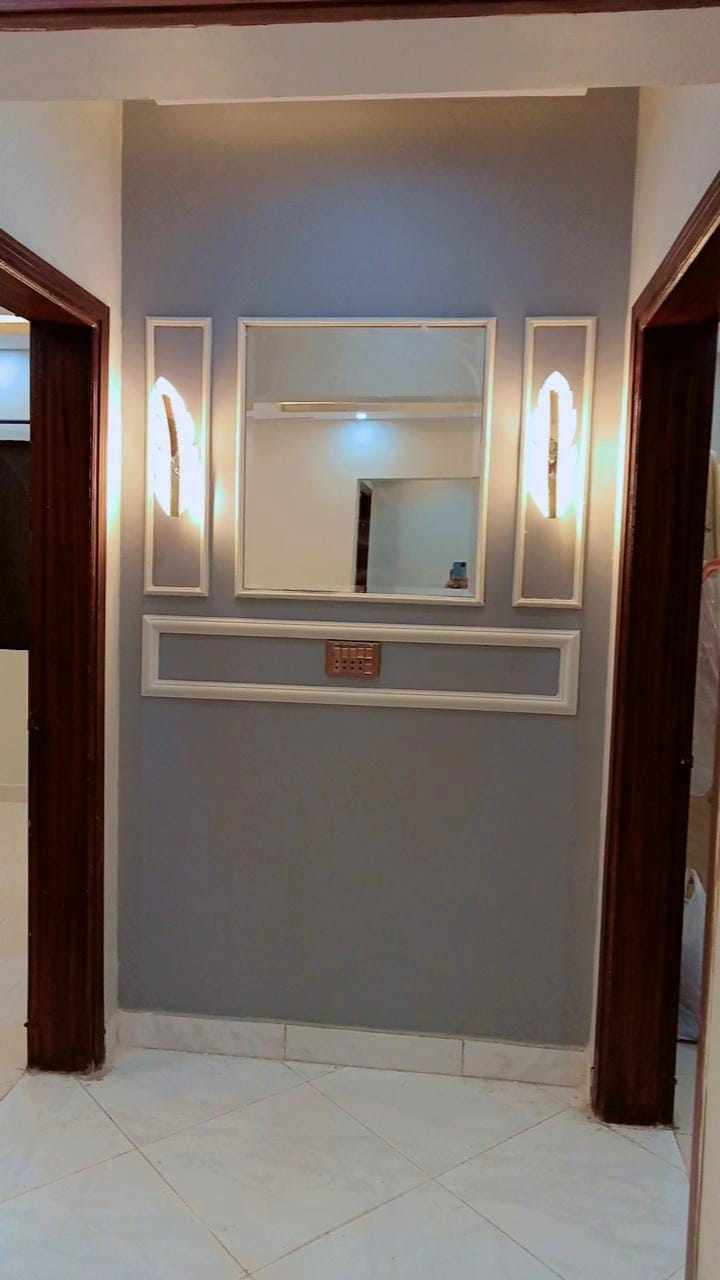 Decorative beading feature wall with modern wall lights installed by Etminaan Services.